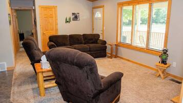 A living room with a brown leather sofa, a wooden coffee table, and a window with blinds.