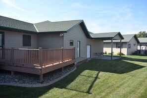 A residential building with a deck, a covered patio, and a well-maintained lawn.