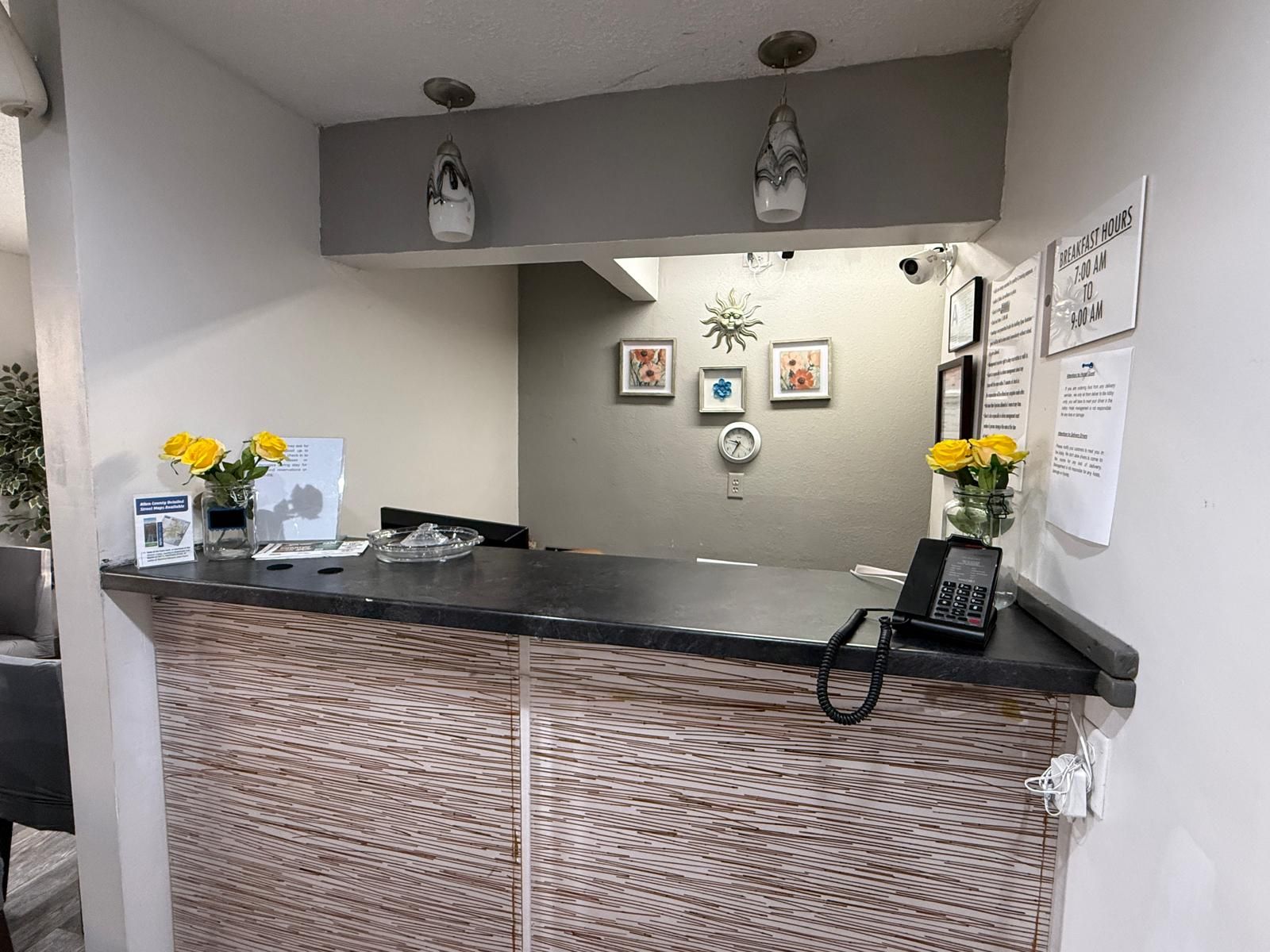 Een receptiebalie met een telefoon, een klok en lijstwerk aan de muur.