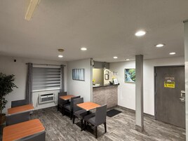 A reception area with a counter, a door marked 'OFFICE FACP,' and a seating area with tables and chairs.