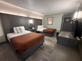 A hotel room with two beds, a desk, and a television.