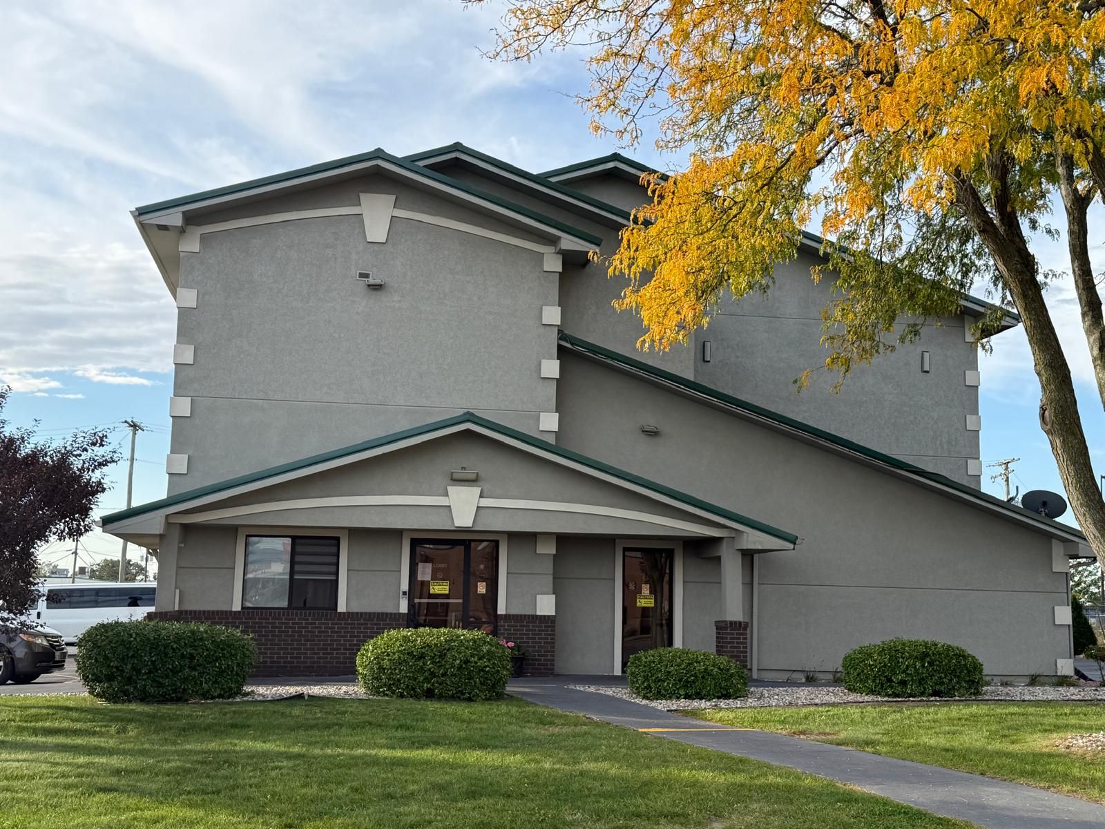A two-story building with a flat roof, a front entrance, and a small porch.
