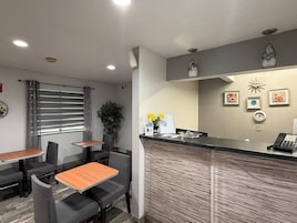 Una zona de recepción con mostrador, sillas, una mesa y una planta.