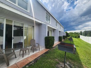 Un edificio moderno con un patio cubierto, mobiliario exterior y un césped bien cuidado.