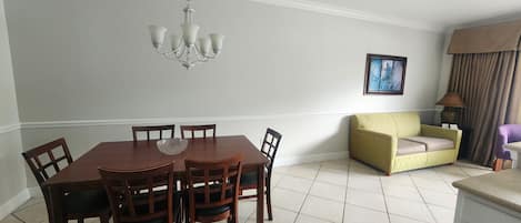 Un espace repas comprenant une table et des chaises en bois, un lustre, un canapé et une lampe.