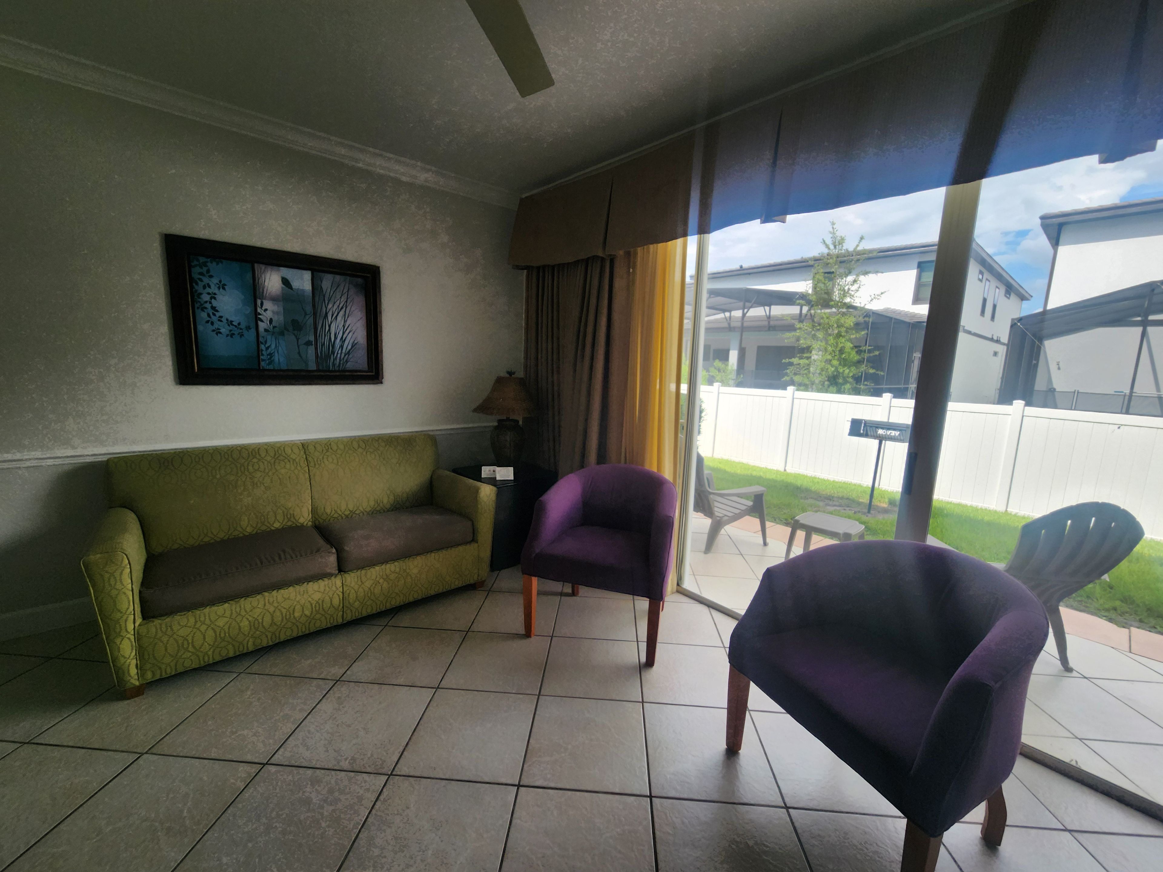 Una sala de estar con un sofá, dos sillones, una lámpara y un cuadro en la pared.