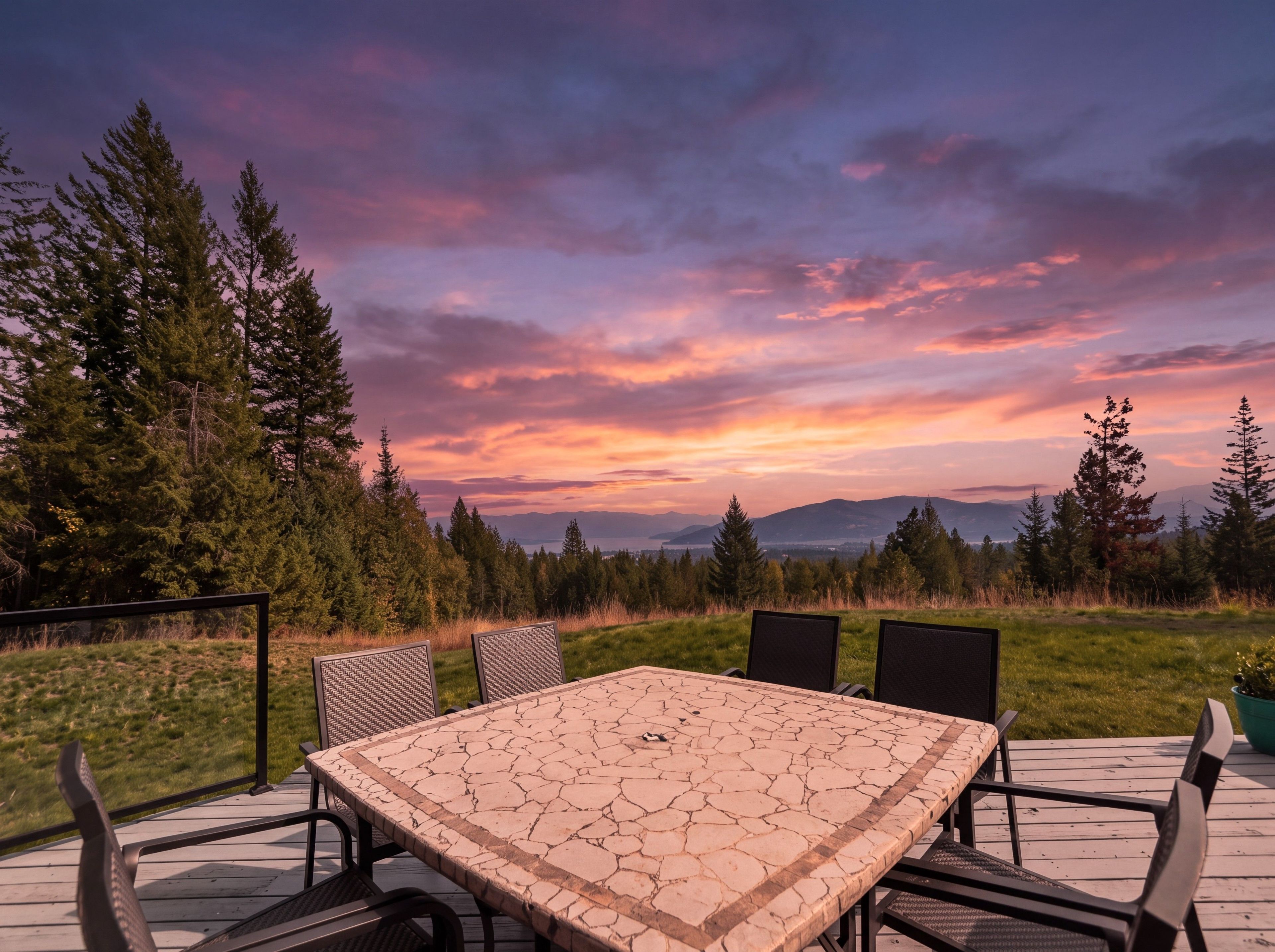 Un espace extérieur aménagé pour les repas, avec une table et des chaises, entouré d’arbres et offrant une vue sur les montagnes.