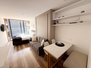 Een modern appartement met een bed, bank, eettafel en inbouwkasten.