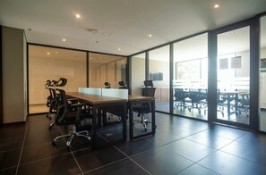 Een vergaderzaal met een lange tafel, stoelen en een glazen scheidingswand.