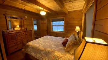 Een houten slaapkamer met een bed, een dressoir en twee ramen.