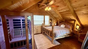 Een knus slaapkamer onder het dak, met houten balken, een bed, een raam en een deur.