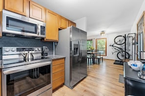 Una cocina moderna con armarios de madera, electrodomésticos de acero inoxidable y un comedor con una bicicleta colgada en la pared.