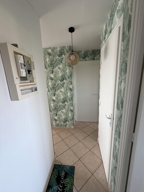 A hallway with a door, a wall-mounted electrical panel, and a welcome mat. - A gem right by the sea 🌊 the Le Panoramic residence in Sainte-Cécile. (Camiers)