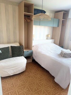 Een slaapkamer met een bed, een kledingkast, een hanglamp en een vloer met een patroon.