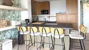 Une cuisine moderne dotée d’un îlot central, de tabourets de bar, de meubles en bois et d’un four à micro-ondes.
