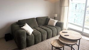 Un salon moderne avec un canapé, une table basse ronde et une grande fenêtre donnant sur un beau paysage.