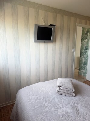 A bedroom with a bed, a television mounted on the wall, and a door leading to another room. - A gem right by the sea 🌊 the Le Panoramic residence in Sainte-Cécile. (Camiers)
