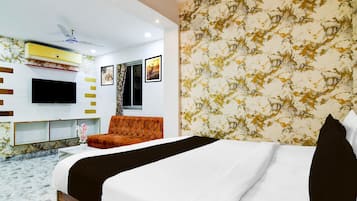 A modern hotel room with a bed, a TV, a ceiling fan, and a wall with a patterned design.