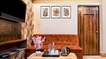 A living room with a flat-screen TV, a sofa, a coffee table with a tray of items, and framed artwork on the wall.