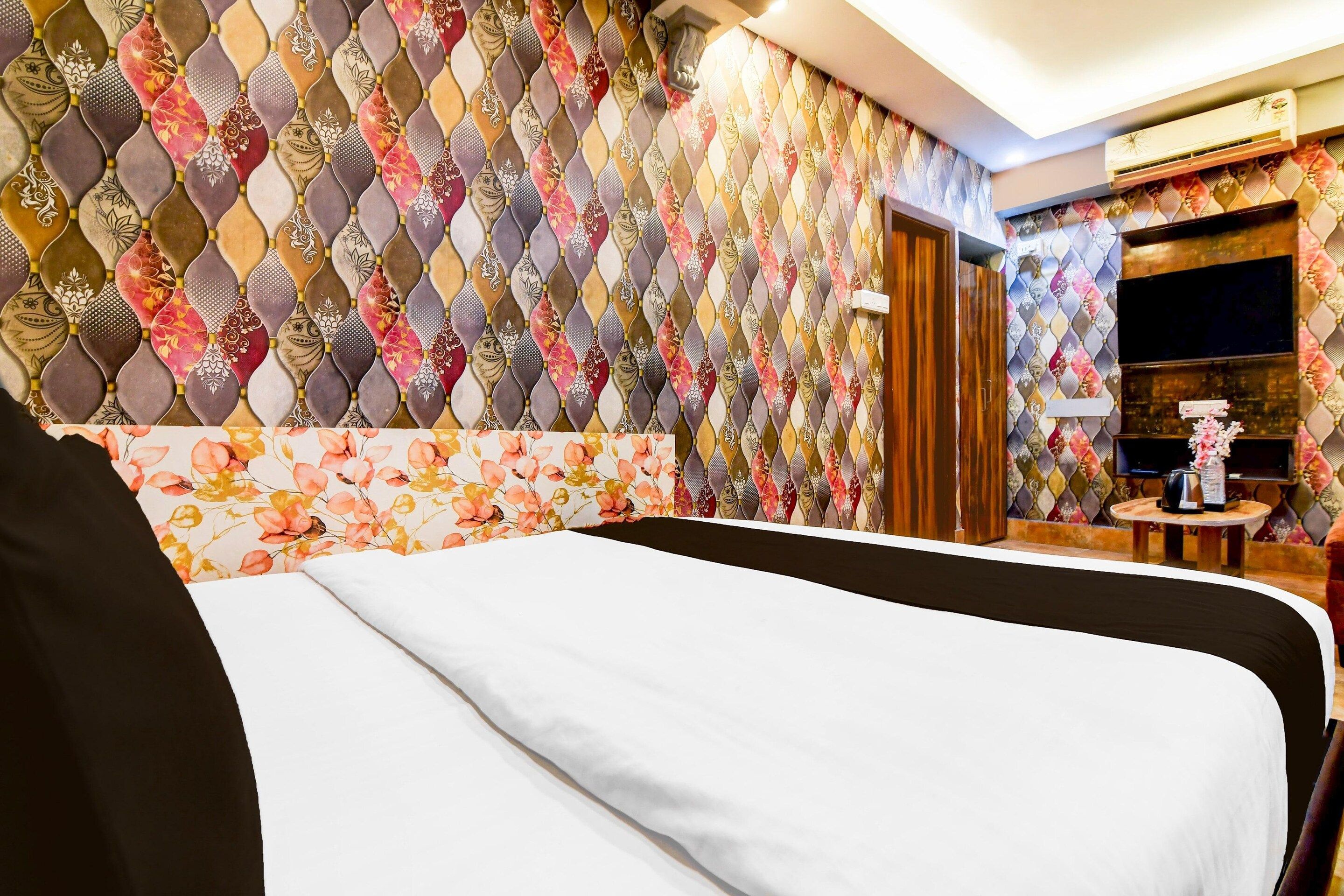 A hotel room with a bed, a wooden side table, and a television.