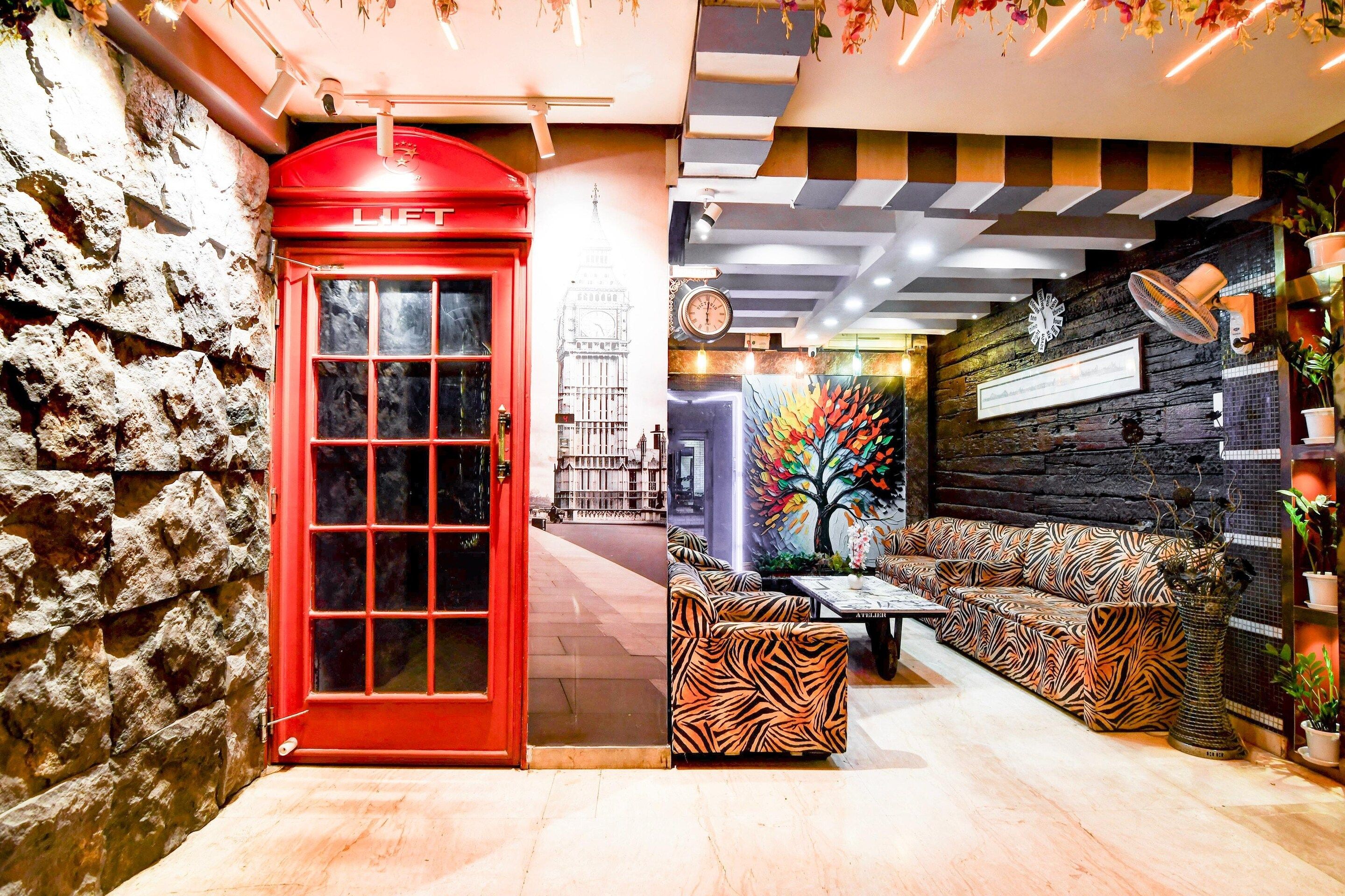 Una cabina telefonica rossa, un divano a righe zebrate e una parete con un orologio e un quadro incorniciato.