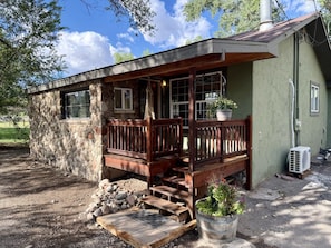 Eine rustikale Holzhütte mit einer Holzdachterrasse, Steinwänden und einem Blumentopf.