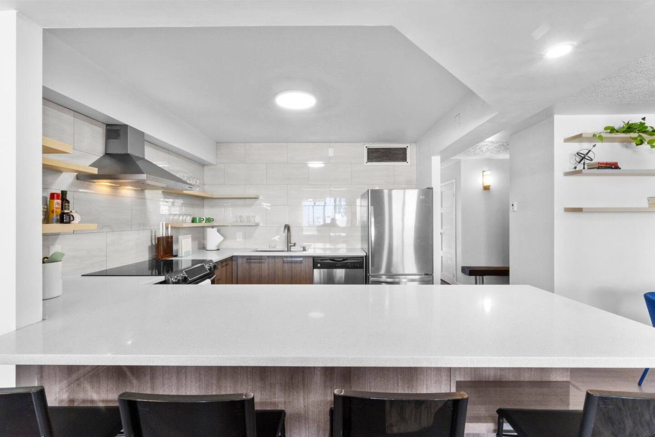 Une cuisine moderne dotée d’un îlot central, d’appareils électroménagers en acier inoxydable et d’un dosseret de carrelage blanc.