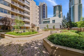 A courtyard with a paved area, benches, and greenery. - 2BR City Retreat | Stampede, BMO & Free Parking (Calgary)