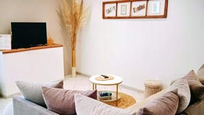 A living room with a sofa, a coffee table, and a TV on a stand.