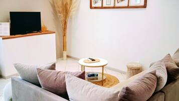 A living room with a sofa, a coffee table, and a TV on a stand.