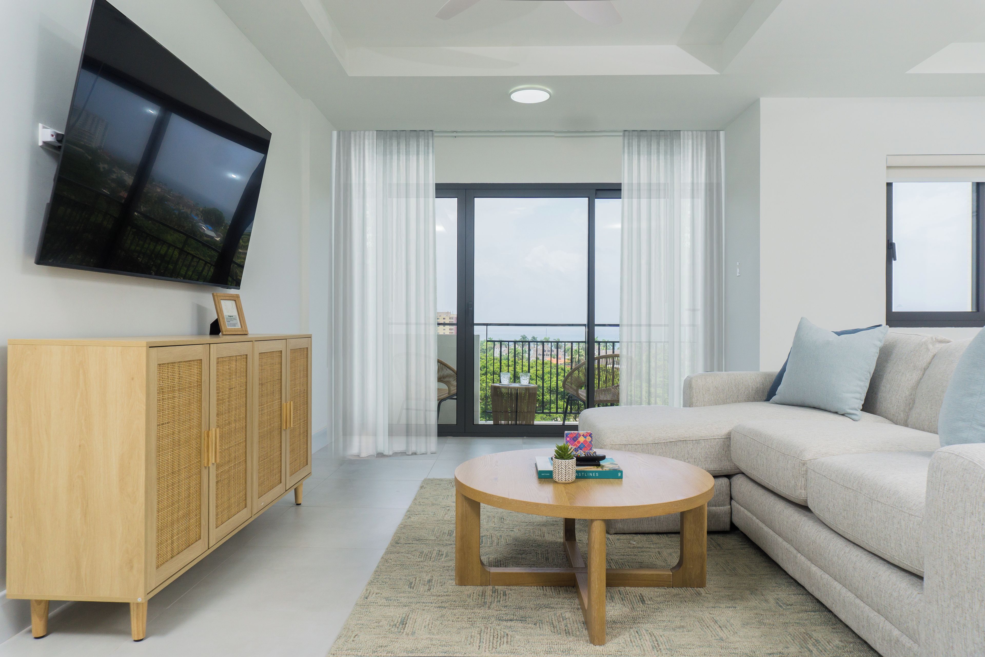A living room with a sofa, a television mounted on the wall, a wooden cabinet, and a round coffee table.