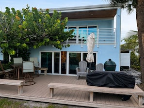 A modern house with a deck, outdoor seating, and a covered grill area. - Direct Oceanfront Retreat with Ocean-to-River Views  Sleeps 8 (Cocoa Beach)