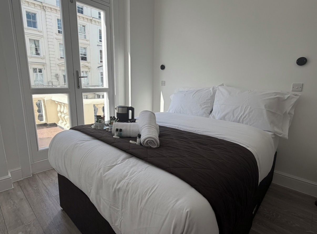 Una habitación de hotel con cama, ventana y vistas a edificios.