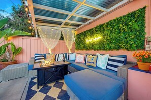 An outdoor seating area with a fire feature, a checkered rug, and a wall with greenery. - Good Vibes & Poolside Nights | San Diego (San Diego)
