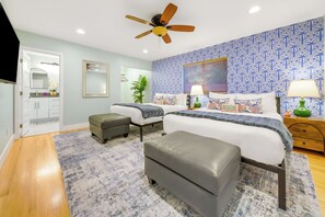 A bedroom with two beds, a ceiling fan, a bathroom with a mirror, and patterned wallpaper. - Good Vibes & Poolside Nights | San Diego (San Diego)