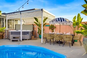 Ein Garten mit Pool, Gartenmöbeln, Grill und einer überdachten Sitzgelegenheit.