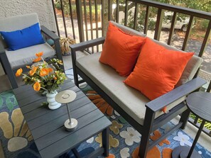 A patio with a sofa, a small table, and a potted plant. - Village House 204 | Relax & Walk to the Beach (Hilton Head Island)