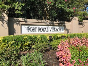 A sign for Port Royal Village with a well-maintained hedge and garden in the foreground. - Village House 204 | Relax & Walk to the Beach (Hilton Head Island)