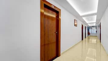 A hallway with a wooden door, white walls, and a tiled floor.