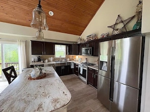 A kitchen with a wooden ceiling, stainless steel appliances, and a large island. - Whispering Woods 2bdrm, 2 bath, tucked in the woods. (Pittsfield)