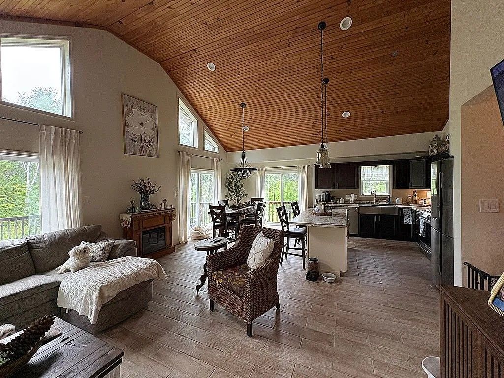 Un amplio espacio habitable con techo de madera, una mesa de comedor y una cocina al fondo.