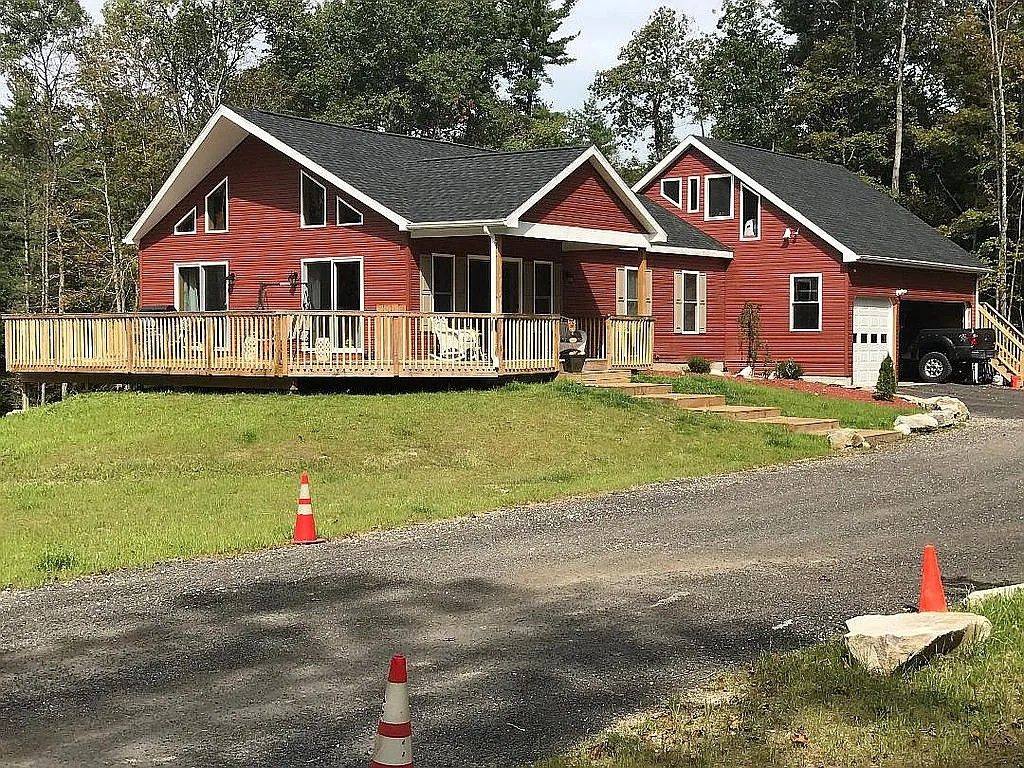 Ein rotes, zweistöckiges Haus mit Veranda und Garage.