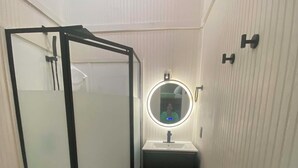 A bathroom with a glass-enclosed shower, a sink with a mirror, and a toilet. - Hummingbird is a Cozy & Quaint 1 bedroom Cabin bordering Ozark National Forest (Dover)