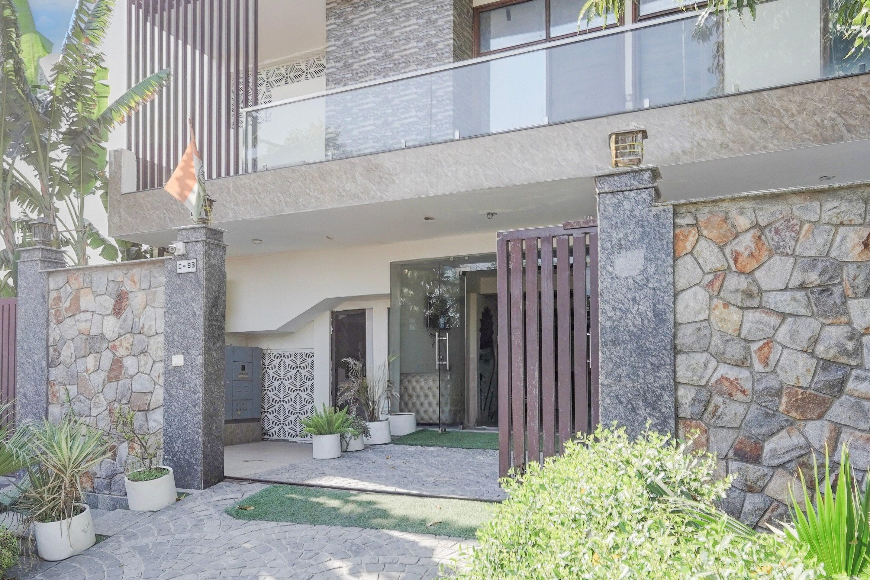 A modern two-story building with a stone facade, a gated entrance, and a small courtyard with potted plants.