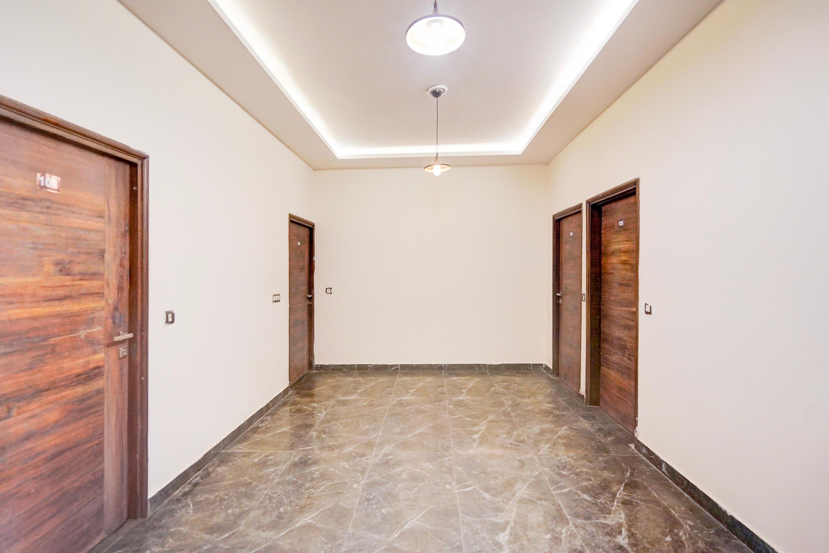A hallway with marble flooring, wooden doors, and a ceiling light fixture.