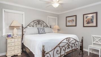 A bedroom with a bed, nightstands, a chair, and wall art.