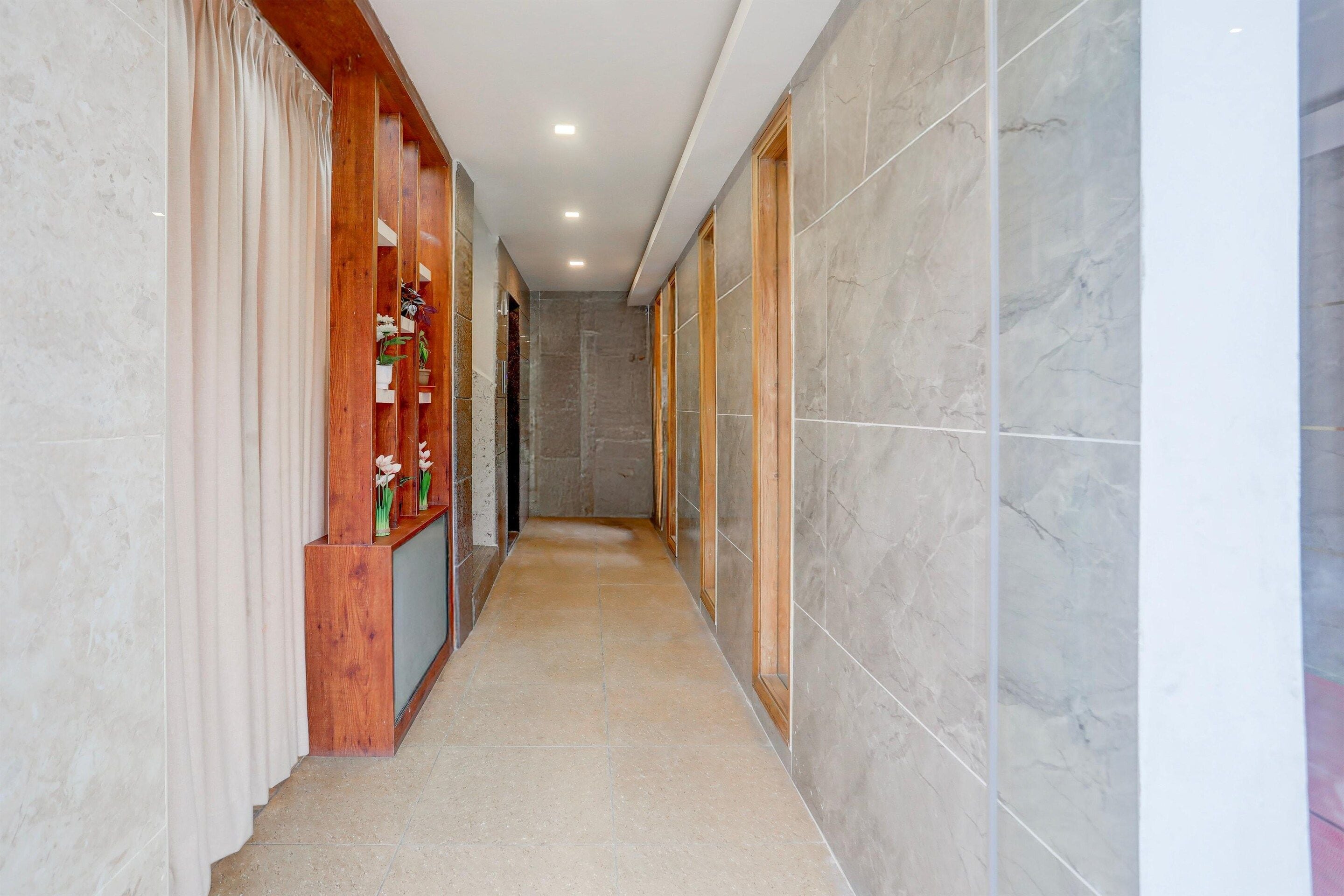 A corridor with marble walls, wooden paneling, and a tiled floor.