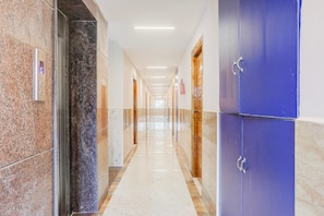 A corridor with a marble floor, doors, and a blue wall. - Super Deluxe Room Hotel Rama Grand (Tirupati)