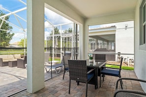 An outdoor patio with a glass enclosure, wicker furniture, and a view of the backyard. - Family Villa Inside Resort (Four Corners)