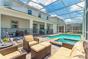 A covered outdoor area with a pool, lounge chairs, and a glass-enclosed patio. - Family Villa Inside Resort (Four Corners)